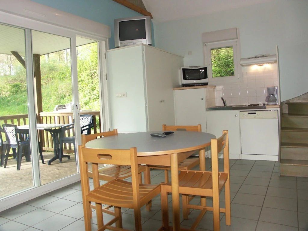 Een compacte keuken met een magnetron, een koffiezetapparaat en een eethoek met een tafel en stoelen.