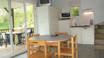 Een compacte keuken met een magnetron, een koffiezetapparaat en een eethoek met een tafel en stoelen.