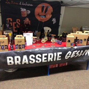A table with a sign reading 'BRASSERIE GESLIN' and various bottles and glasses on it.