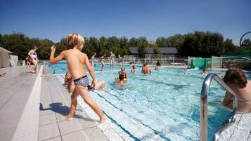 A swimming pool with people in the water and on the deck.