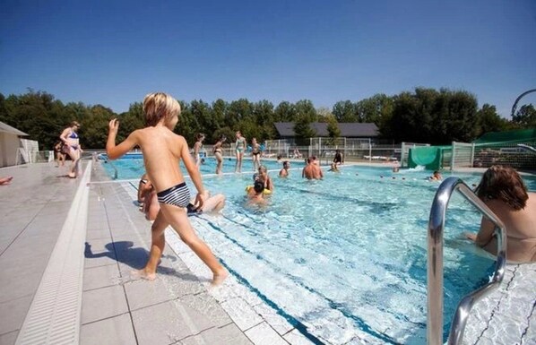 A swimming pool with people in the water and on the deck.