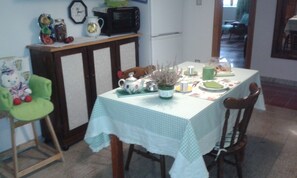 Un coin repas avec une table dressée pour deux personnes, une horloge et un four à micro-ondes fixé au mur.