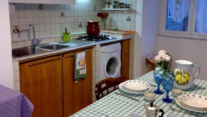 A compact kitchen with a washing machine, a stove, and a sink. - At Anita's, a bright apartment with easy access to the historic center. (Roma)