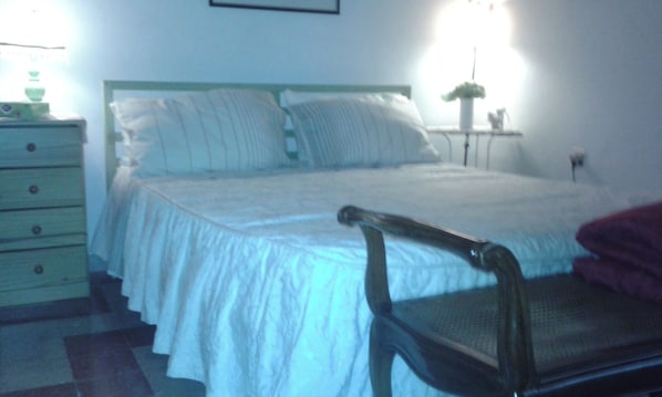 Ein Schlafzimmer mit einem Bett, einem Sessel, einer Kommode und einem Nachttisch.