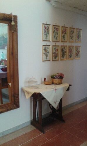Ein Zimmer mit einem Holztisch, einem Spiegel und einer Wand mit gerahmten Blumenbildern.