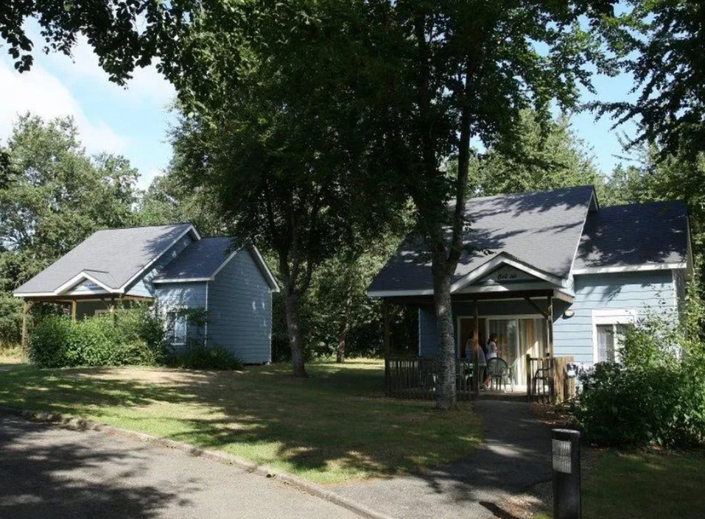 Een woonwijk met twee huizen, elk met een veranda en een kleine tuin.