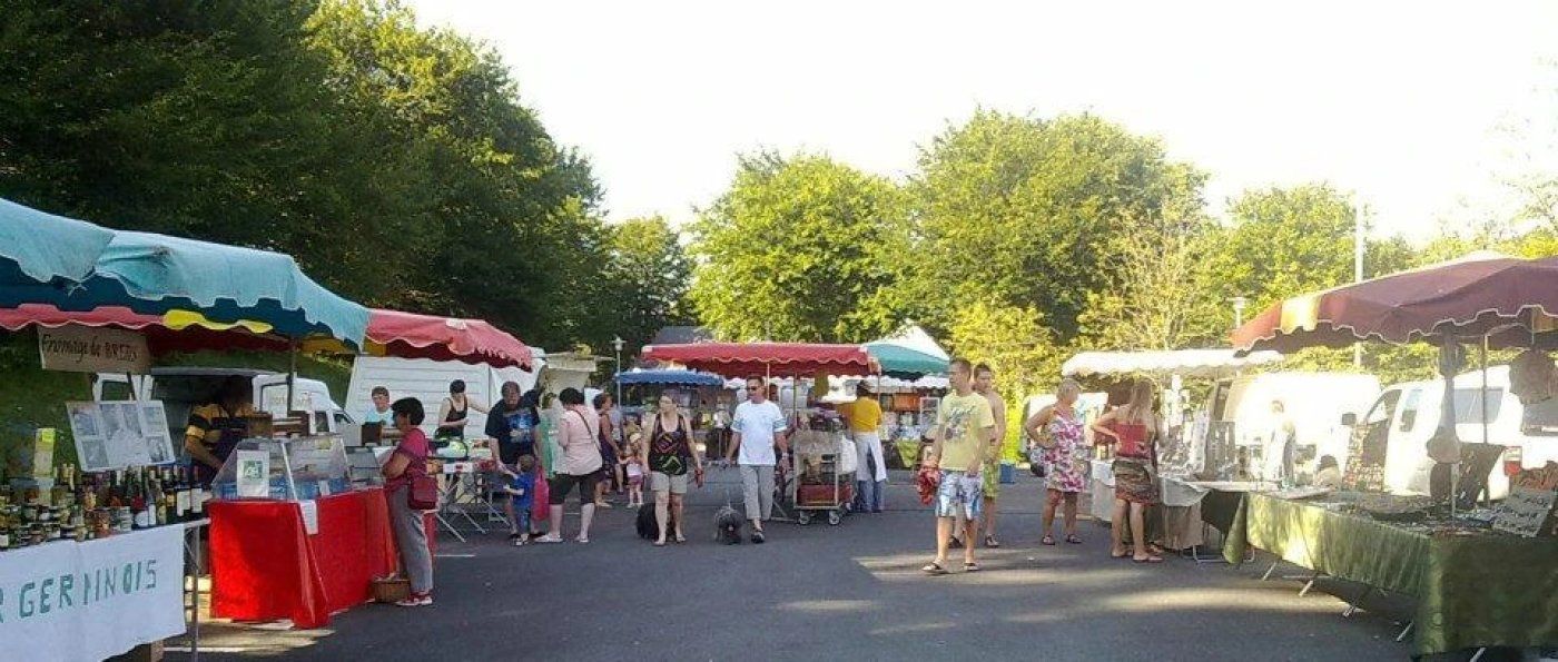 Een markt in de open lucht met verschillende kraampjes en mensen die rondkijken.