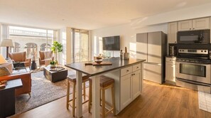 A modern kitchen with a central island, stainless steel appliances, and a view of a bridge outside. - Luxury 2BR Apartment Balcony, Gym & Parking (Cleveland)