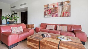 Ein modernes Wohnzimmer mit einem roten Ledersofa, einem Holztisch und einem großen abstrakten Gemälde an der Wand.