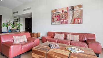 Una sala de estar moderna con un sofá de cuero rojo, una mesa de centro de madera y un cuadro abstracto grande en la pared.