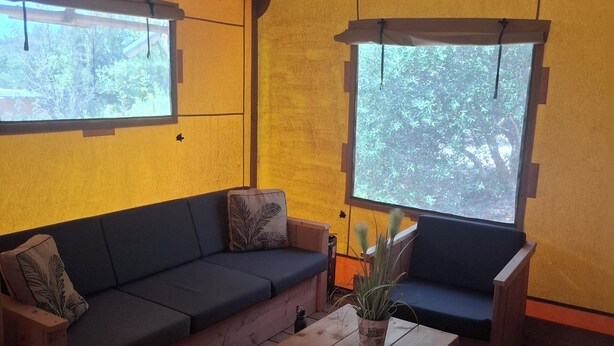 A room with a wooden floor, a sofa, a coffee table, and two windows with curtains. - Couple Poco Novo Glamping Lodge in Loulé Algarve for 1-2 people (Loulé)