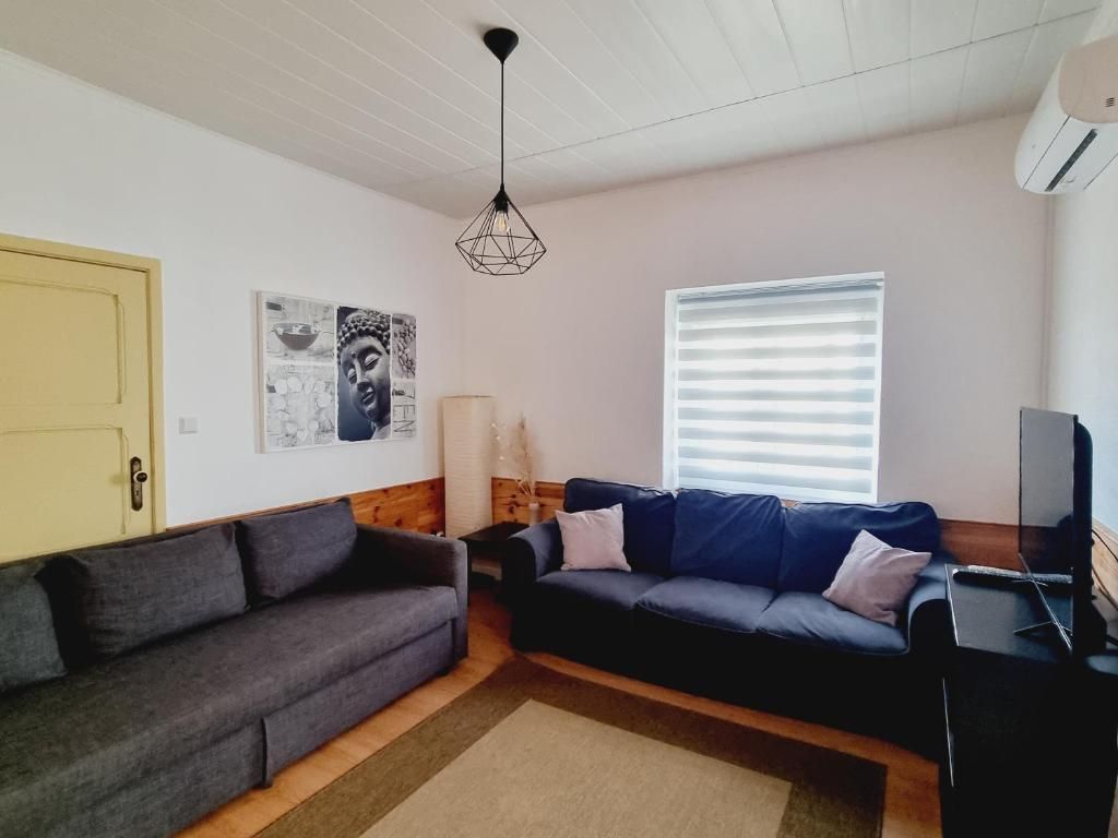 Ein Wohnzimmer mit zwei Sofas, einem Fernseher und Kunstwerken an der Wand.