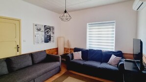 Ein Wohnzimmer mit zwei Sofas, einem Fernseher und Kunstwerken an der Wand.
