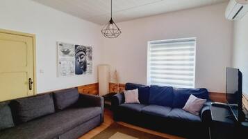 Ein Wohnzimmer mit zwei Sofas, einem Fernseher und Kunstwerken an der Wand.