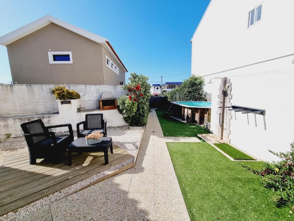 Ein Wohnhaus mit einer Terrassenfläche, Gartenmöbeln im Freien, einem kleinen Pool und einem gepflegten Rasen.