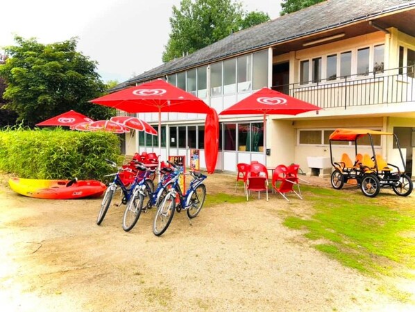 A building with a covered outdoor seating area, bicycles, and a golf cart.