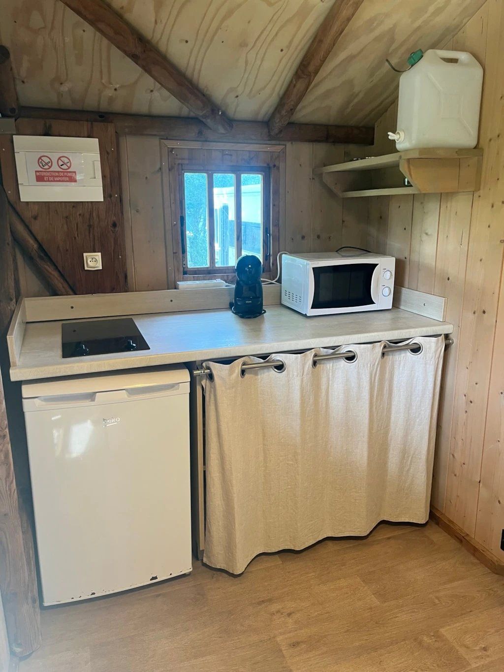 A compact kitchen with a microwave, a coffee maker, and a small refrigerator.