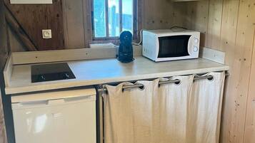 A compact kitchen with a microwave, a coffee maker, and a small refrigerator.