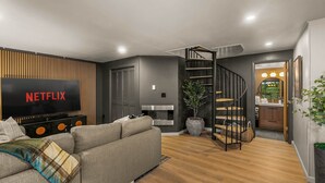Uma sala de estar moderna com televisão de tela plana, uma escada e uma área de cozinha.