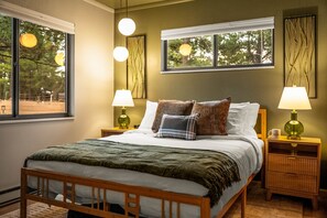 Een slaapkamer met een houten bed, twee nachtkastjes, een wandlamp en een raam met zonwering.