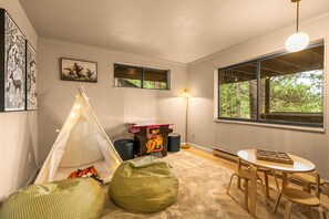 Een gezellige kamer met een tent, relaxfauteuils, een tafel en een lamp.