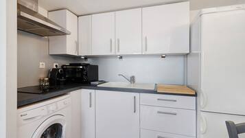 A compact kitchen with a washing machine, a microwave, a sink, and a refrigerator.