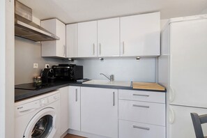 A compact kitchen with a washing machine, a microwave, a sink, and a refrigerator.
