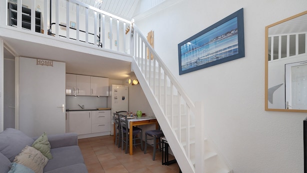 A compact living space with a kitchen, dining area, and a staircase leading to an upper level.