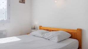 A bedroom with a wooden headboard, a bed with white bedding, a bedside lamp, and a wall-mounted light fixture.