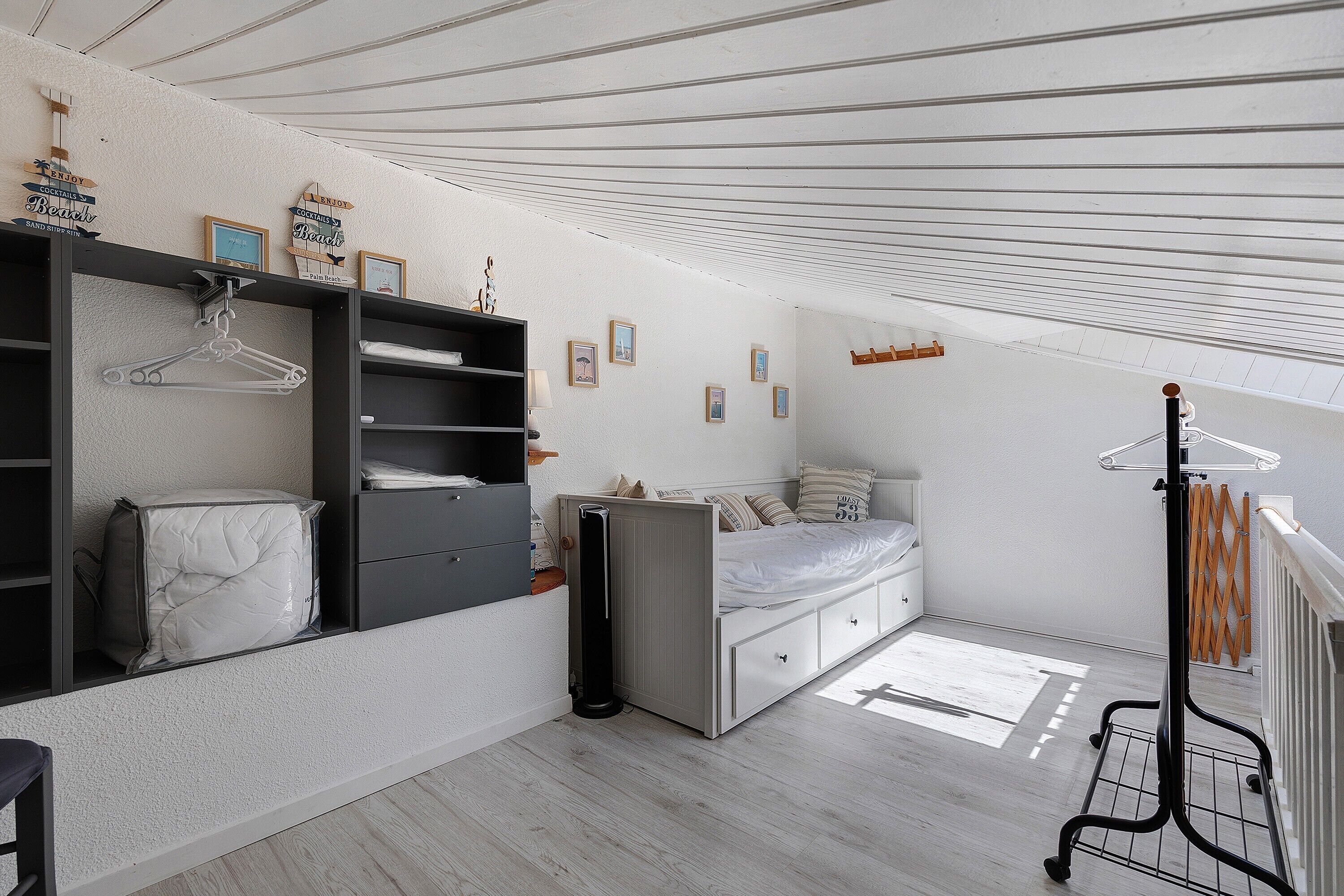 A bedroom with a bed, a wardrobe, a radiator, and a window.