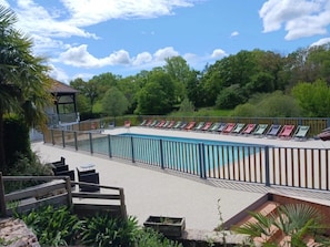 A pool area with lounge chairs and a small pavilion.