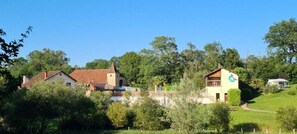 A rural house with a stone tower, surrounded by lush greenery and trees.