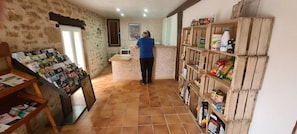 A room with a tiled floor, a wooden counter, and shelves stocked with various food items.