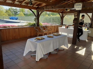 A covered outdoor area with a table set for a meal, a sign reading "CABINE TELEPHONIQUE," and a person standing near a counter.