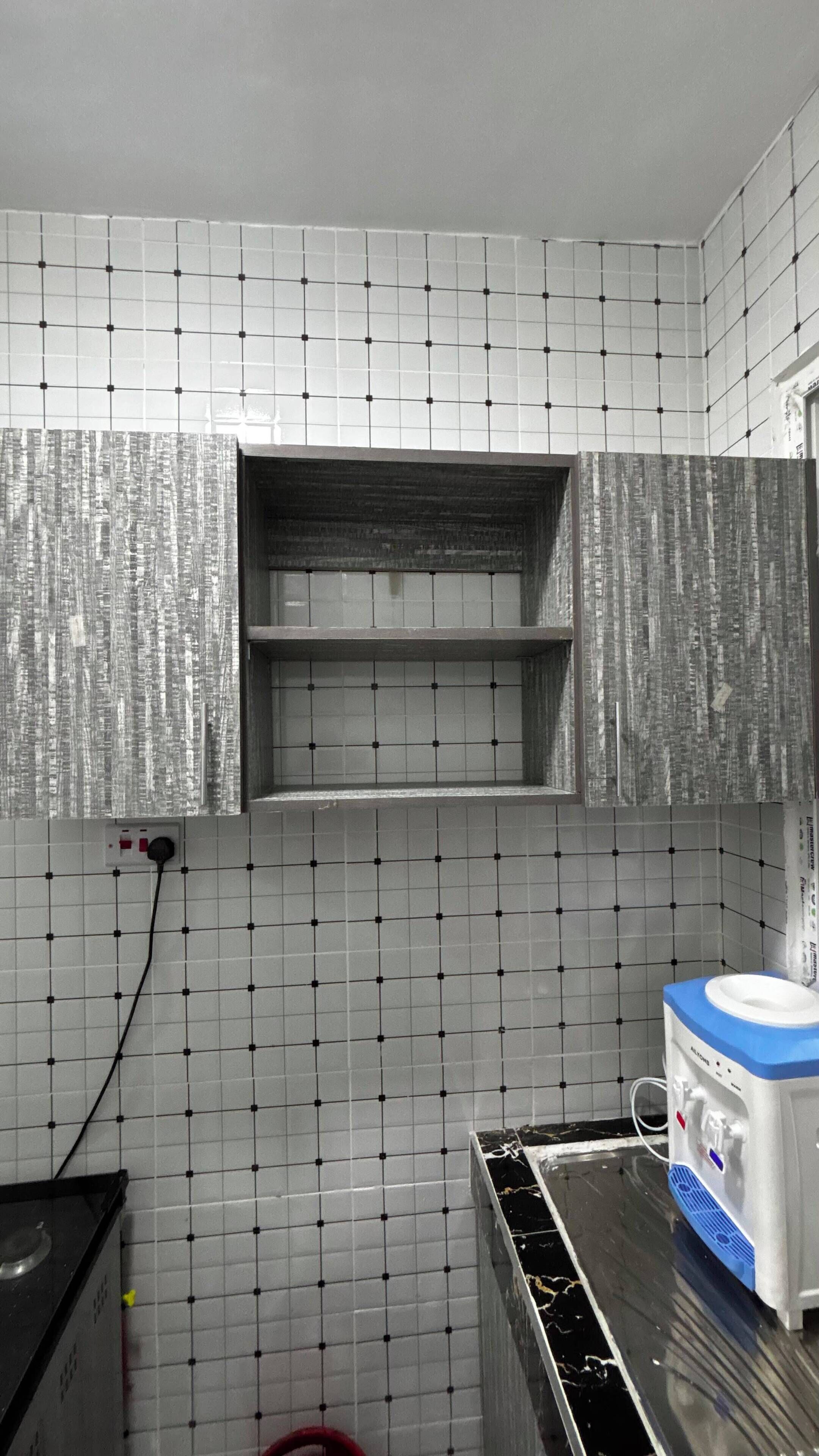 A kitchen with tiled walls, a stove, and a water dispenser.