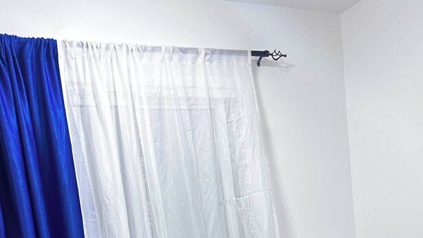 Una cama con cabecera azul, ropa de cama blanca y dos almohadas amarillas.