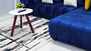 Una sala moderna con un sofá modular, una mesita redonda y una alfombra estampada.