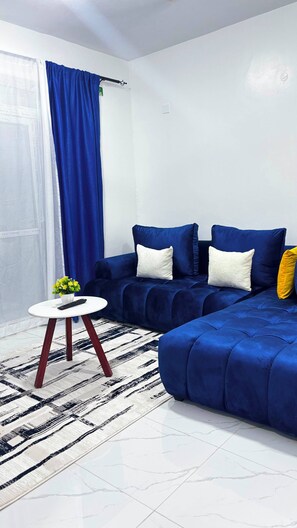 Ein modernes Wohnzimmer mit einer Eckcouch, einem kleinen runden Tisch und einem Teppich mit Muster.