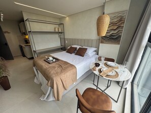 Ein modernes Hotelzimmer mit Bett, Nachttisch und einem Essbereich mit Tisch und Stühlen.