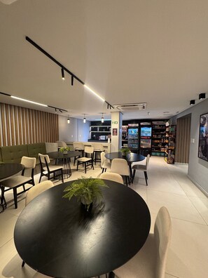 Ein modernes Interieur mit einem runden Tisch im Vordergrund, einem grünen Sofa und einer Bar im Hintergrund.