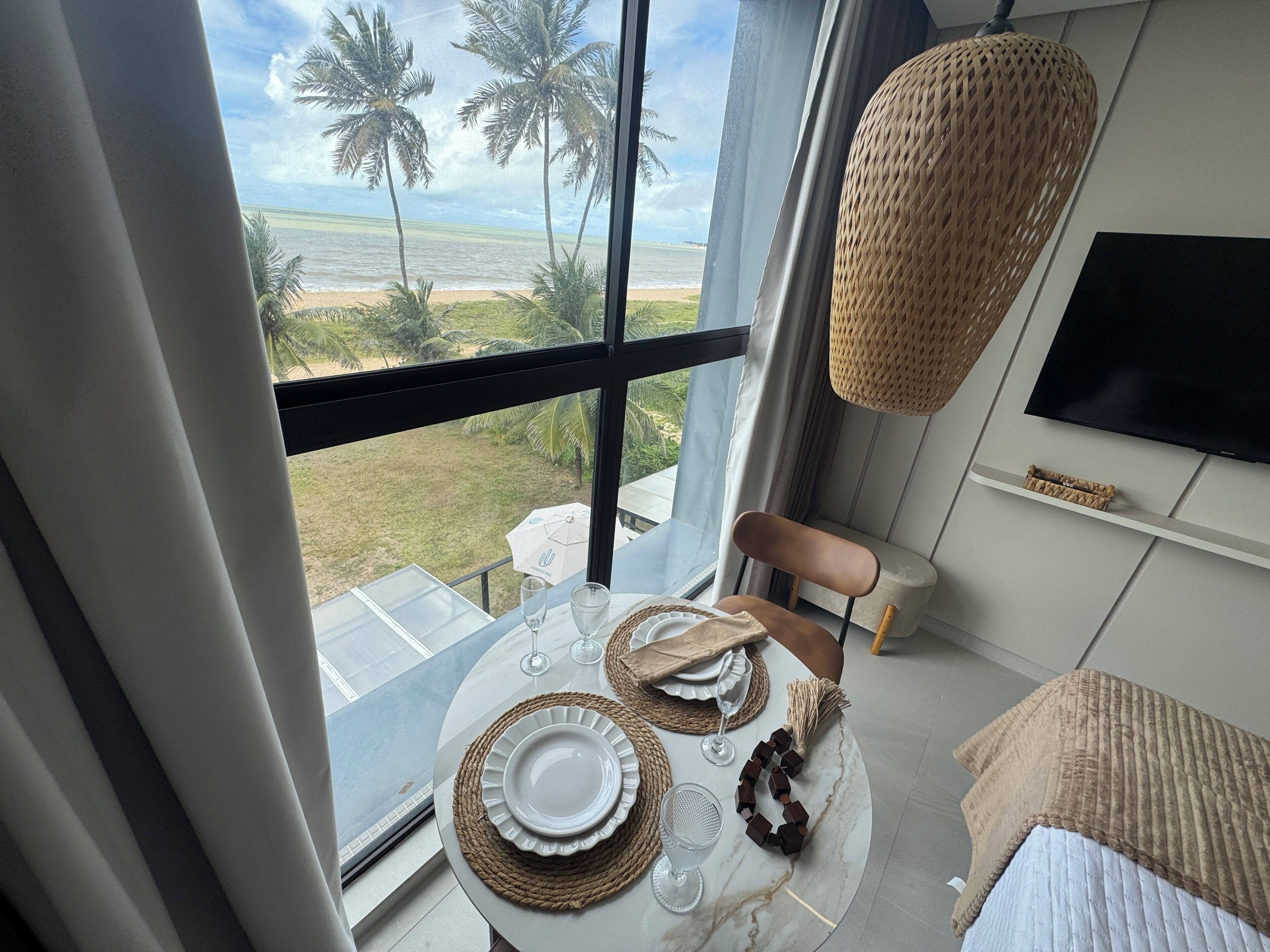 A dining area with a table set for two, overlooking a beach view.