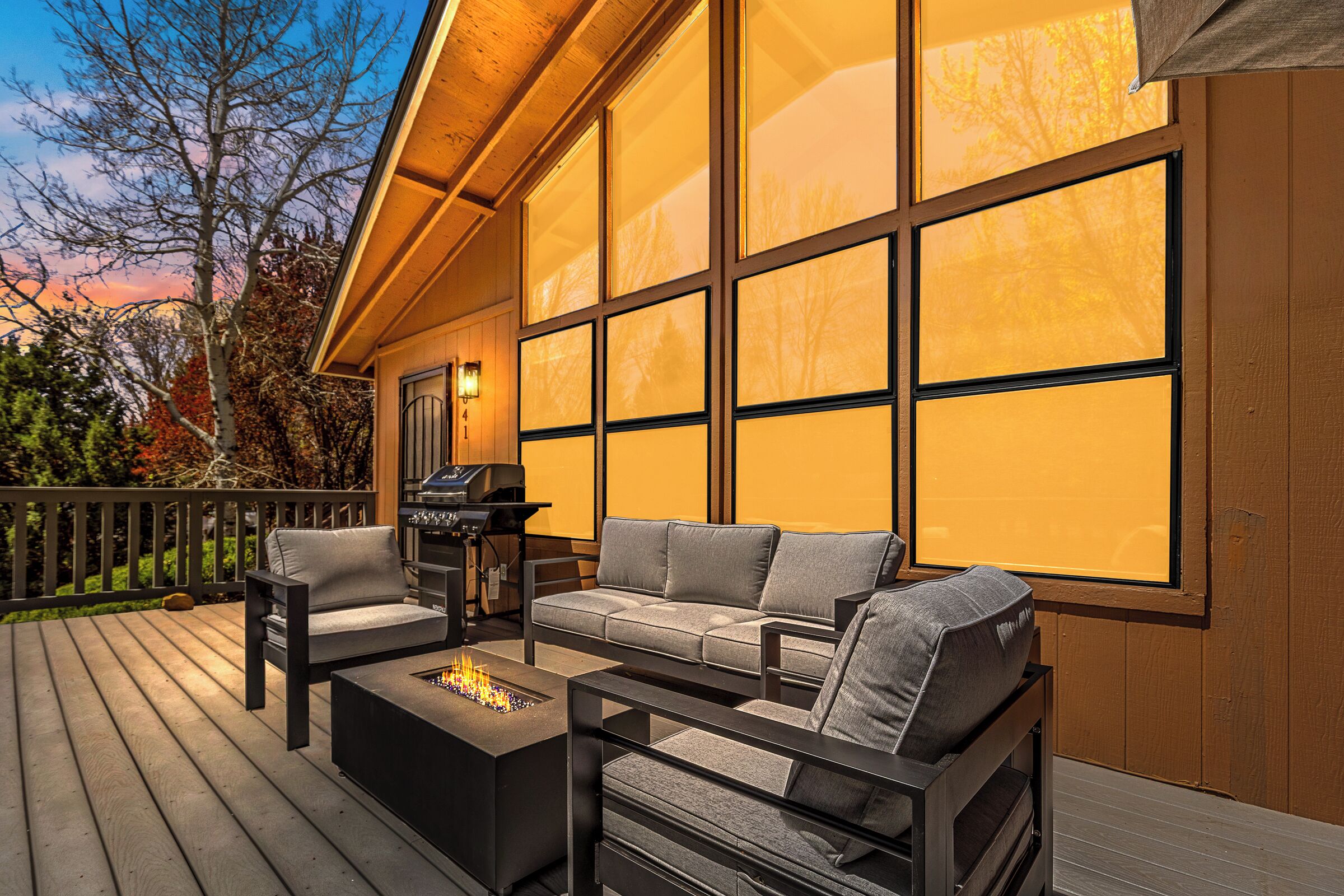A deck with a sofa, chairs, and a grill.