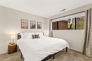 Une chambre à coucher avec un grand lit, deux lampes de chevet, une petite plante et trois tableaux encadrés accrochés au mur.