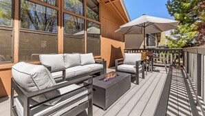 Une terrasse avec un canapé, des chaises, un foyer extérieur et un parasol.