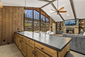 A spacious kitchen with a large island, wooden cabinetry, and a stone fireplace. - Cozy 2 BD/1BTH - Family - Country Club - A/C (Flagstaff)