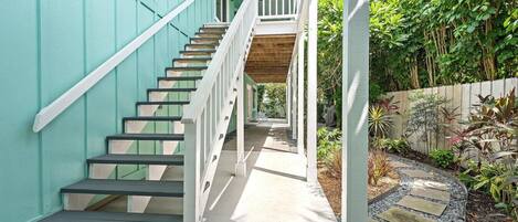 A staircase leading to a covered porch with a view of a garden.