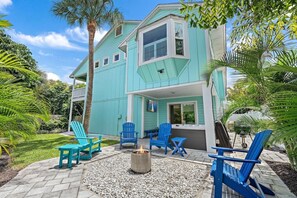 A two-story house with a covered patio area featuring outdoor seating and a fire pit. - Sleeps 10 • Hot tub • Games • 5 Mins to Beach (Jupiter)
