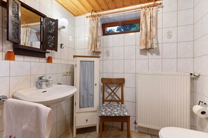 Un baño con lavamanos, espejo, ventana y una silla.