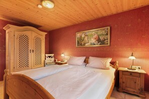Un dormitorio con una cama de madera, dos mesitas de noche con lámparas, un armario de madera y un cuadro en la pared.