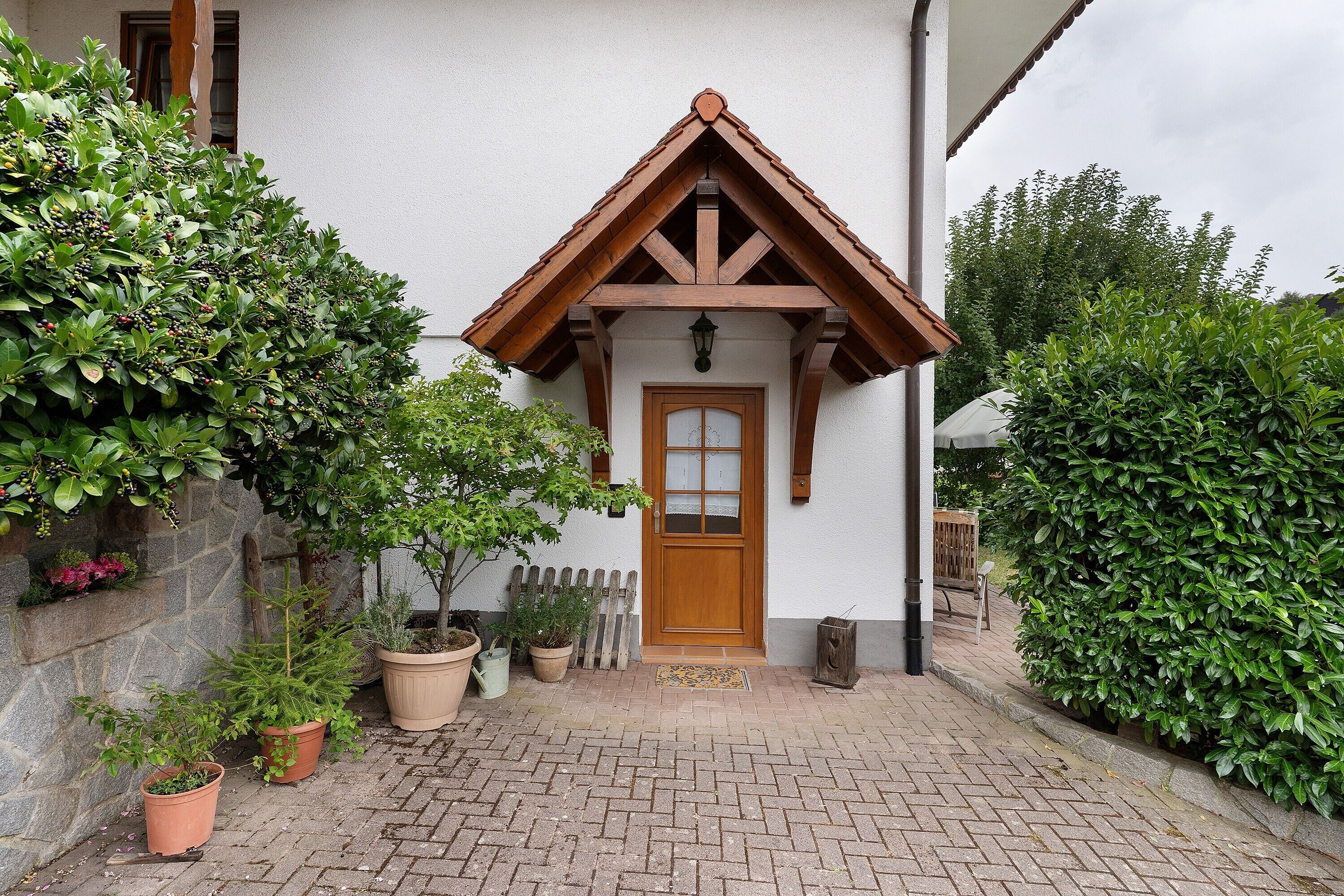 Ein traditionelles Gebäude mit einem Holmgiebel, einem kiestein befestigten Eingangsbereich und Topfpflanzen.